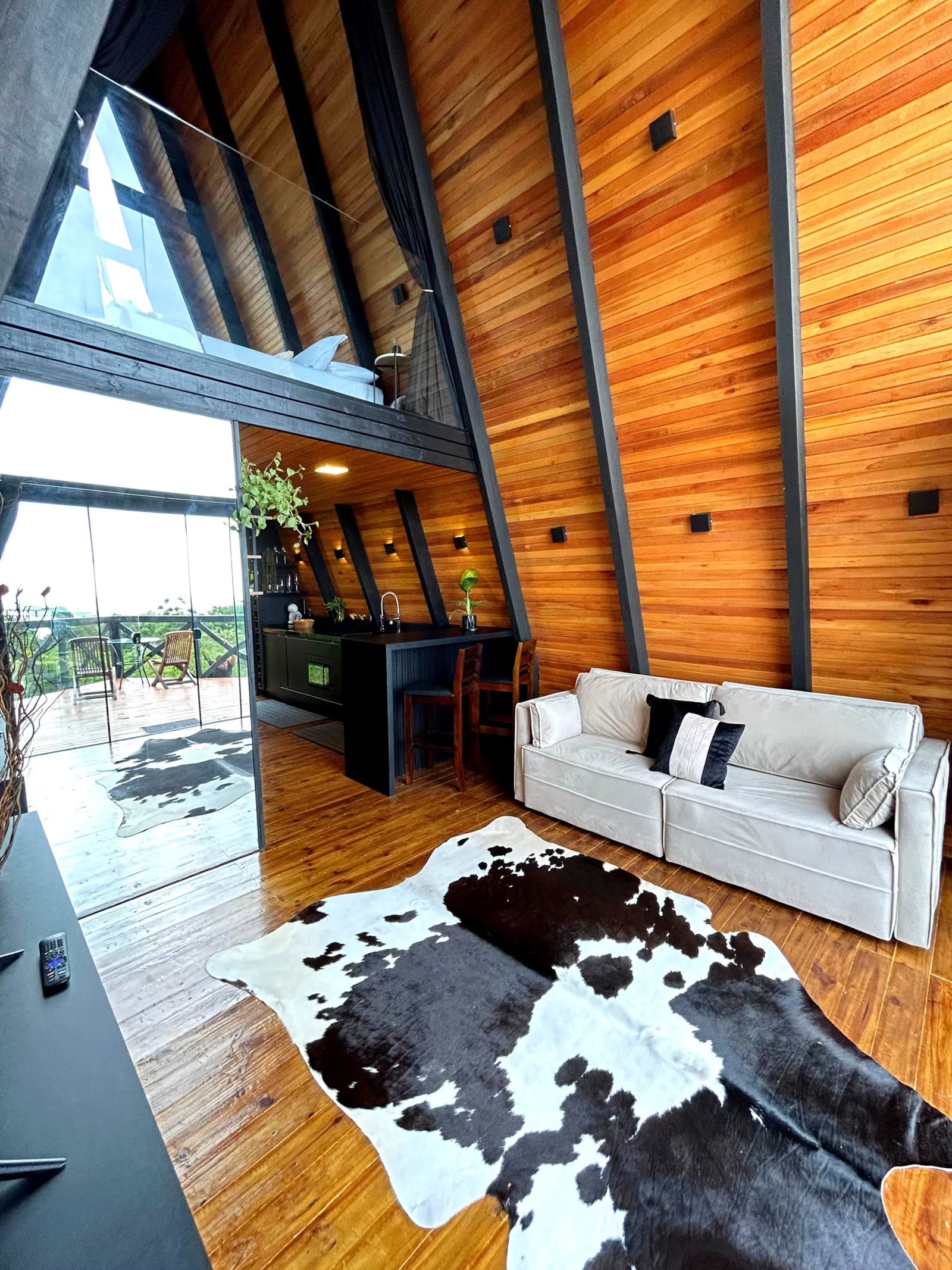 Living do chalé com tapete de couro, sofá e vista para o deck e o mar